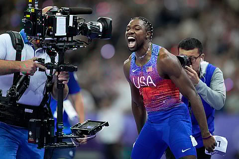 Noah Lyles screams at a tv camera celebrating after winning the gold medal